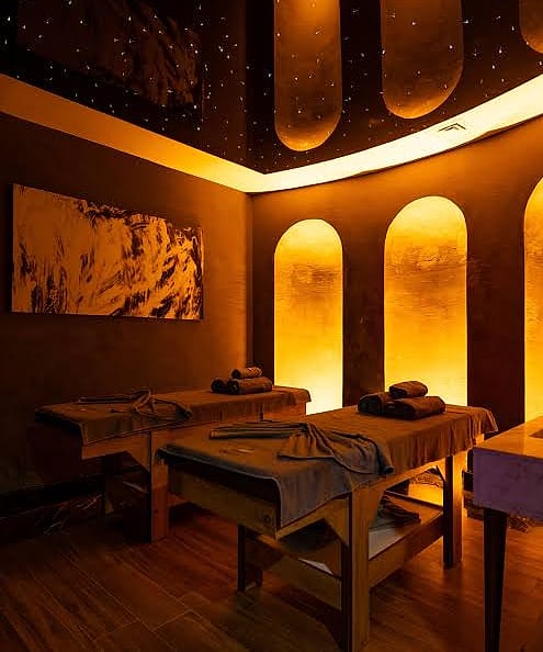 Private spa suite with two massage tables and warm amber niches under a starlit ceiling